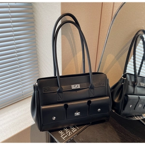 Close-up of black leather tote bag with silver metal buckles and three utility front pockets