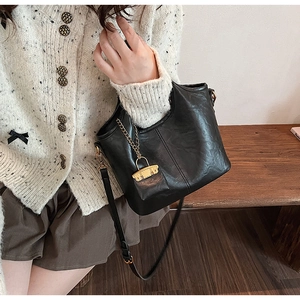 Détail du sac seau noir en similicuir mat avec chaîne dorée et cadenas décoratif