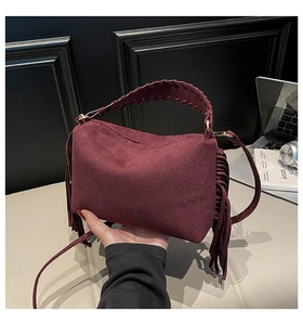 Detail of burgundy suede bag featuring long fringe decor and hand-woven handle textures