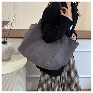 Detail of dark grey tote bag with matte texture shown on shoulder for daily commute