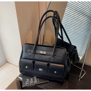 Detail of black faux leather tote bag with silver metal twist lock and triple front pockets