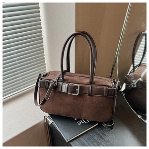 Detailed view of the dark brown suede bucket bag with leather straps on a wooden table