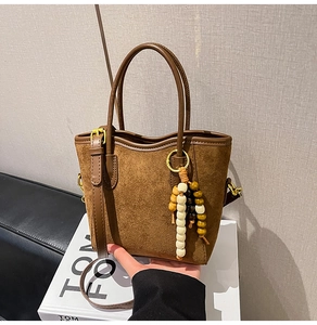 Gros plan d'un sac cabas en daim marron avec des charms en perles et des anses en cuir