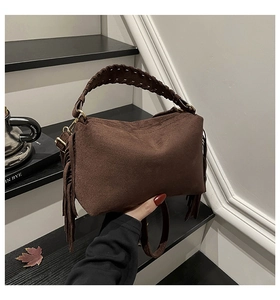 Detail of brown suede handbag with fringe tassels and woven handle in autumn setting
