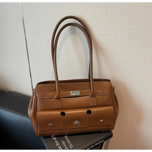 Detail of a brown leather tote bag with three utility pockets and metal twist locks