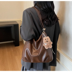 Detail showing high-quality brown vintage Hobo bag with plush teddy bear pendant
