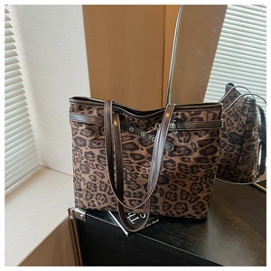 Détail du sac cabas léopard avec anses en cuir marron et détails d'œillets métalliques