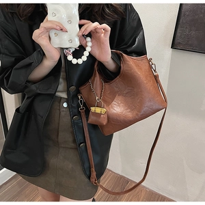 Détail du sac seau marron en cuir grainé avec coutures décoratives et mini pochette