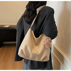 Detail view of beige textured tote bag with cute plush bear charm on side strap