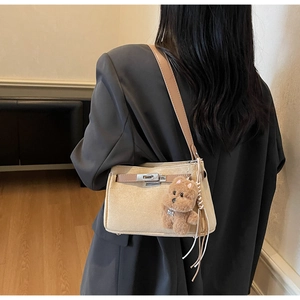 Detail of beige suede shoulder bag with brown leather accents and cute bear keychain