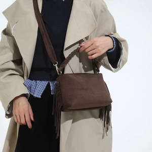 Detail of dark brown suede fringe handbag with woven handles and a detachable strap
