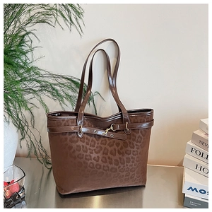 Détail d'un sac cabas léopard avec lanière en cuir marron et boucle dorée élégante