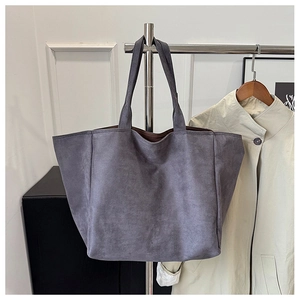 Close-up of large smoke grey suede tote bag hanging next to a classic beige trench coat