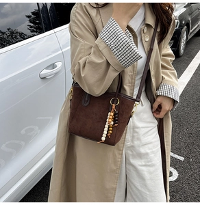 Détail d'un sac seau en daim marron avec des charms en perles colorées et dorure chic