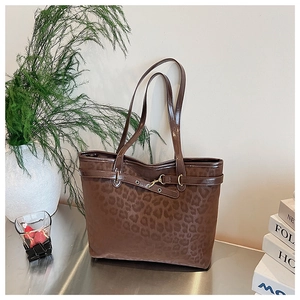 Détail d'un sac cabas imprimé léopard avec sangles en similicuir marron et boucles en métal