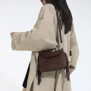 Close-up of brown suede crossbody bag featuring retro fringe and woven edge details