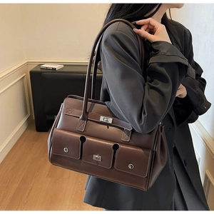 Detail view of large vintage brown tote bag with three front pockets and silver buckles