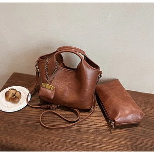 Ensemble de trois sacs seaux marron caramel rétro posés sur une table en bois brun