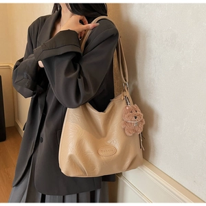 Detail of pleated beige shoulder bag featuring Banatu leather logo and bear charm
