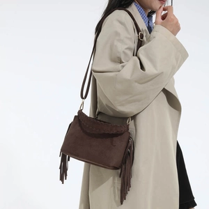 Detail of vintage brown suede crossbody bag with fringe tassels and woven flap accents