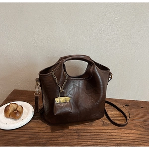 Vue détaillée d'un sac seau en cuir PU marron foncé avec mini pochette sur bois