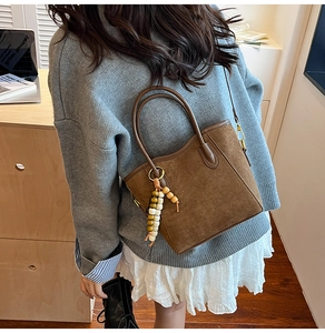Détail d'un sac cabas en daim marron avec franges en perles de bois et anse en cuir