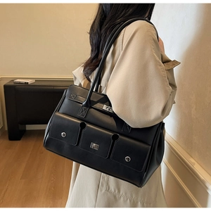 Detail of black leather tote bag with three front pockets and silver twist lock hardware