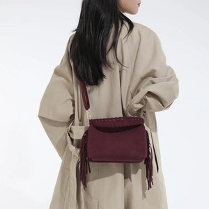 Detail showing burgundy suede crossbody bag with fringe tassels on khaki trench coat