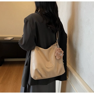 Detail of beige faux leather tote bag showing soft texture and cute brown bear charm