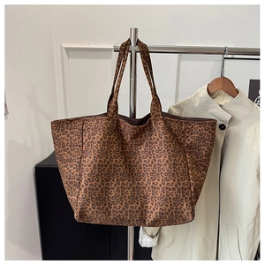 Close-up of leopard print tote bag with thick shoulder straps on a display hanger