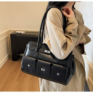 Classic black leather tote bag with three front pockets shown styled on a model's shoulder