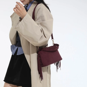 Detail of vintage burgundy matte crossbody bag featuring side tassels and woven edges