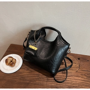 Détail du sac seau noir en similicuir texturé avec petit porte-monnaie sur chaîne dorée