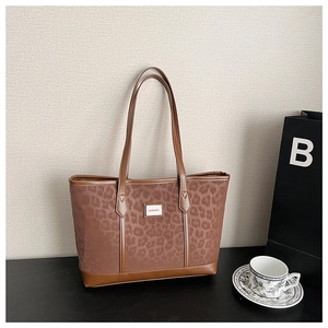 Gros plan du sac cabas à motif léopard avec écusson mimiso sur fond texturé
