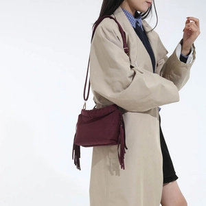 Detail of burgundy frosted fringe handbag showing long tassels and suede texture