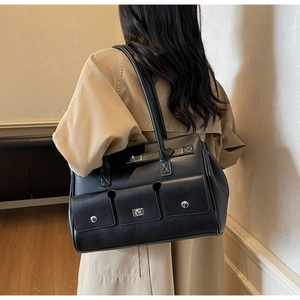 Close-up of black leather tote bag with functional magnetic flap pockets and metal hardware