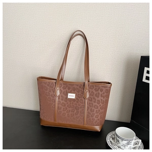 Détail du sac cabas léopard avec anses en cuir marron et badge logo mimia