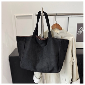 Detail of a large black matte tote bag with brown lining hanging on a metal stand