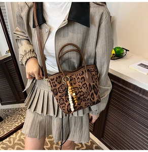 Détail du sac seau en daim léopard avec gland en perles de bois et doubles poignées