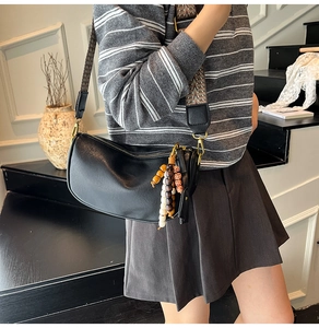 Detailed side view of black crescent bag with ethnic pattern wide strap and wooden beads