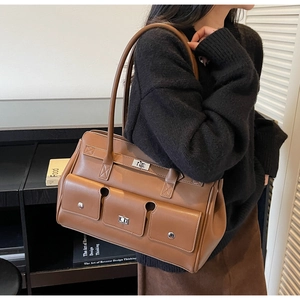 Detail of vintage brown multi-pocket tote bag featuring silver twist-lock and rivet accents
