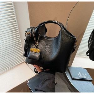 Détail du sac cabas demi-lune noir avec mini pochette chaîne dorée et coutures fines