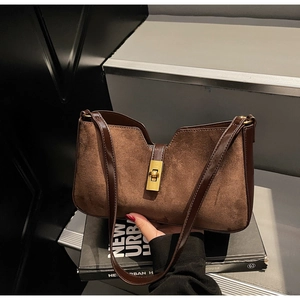 Détail d'un sac seau vintage en daim marron avec fermoir doré et design en V chic