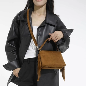Close-up of brown suede crossbody bag with fringe tassels and woven top handle