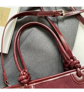 Close-up of knotted leather handle on a burgundy bucket bag with metallic buckle detail