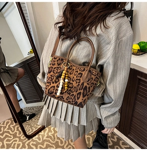 Détail du sac seau à imprimé léopard avec breloque à franges en perles et texture rétro
