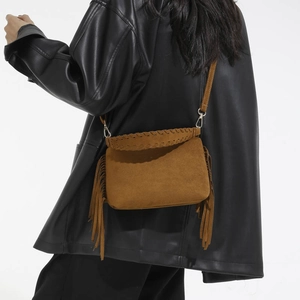 Detailed back view of model wearing a brown frosted suede crossbody bag with long tassels