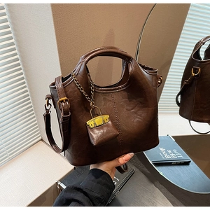 Détail du sac seau vintage marron en cuir huilé avec mini charme et chaîne dorée