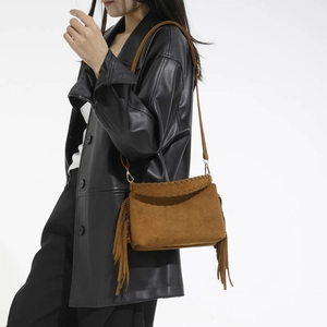 Close-up of brown suede crossbody bag with tassels and woven leather edge details