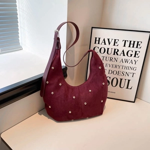 Borsa hobo in pelle scamosciata bordeaux con borchie e tracolla regolabile sul tavolo